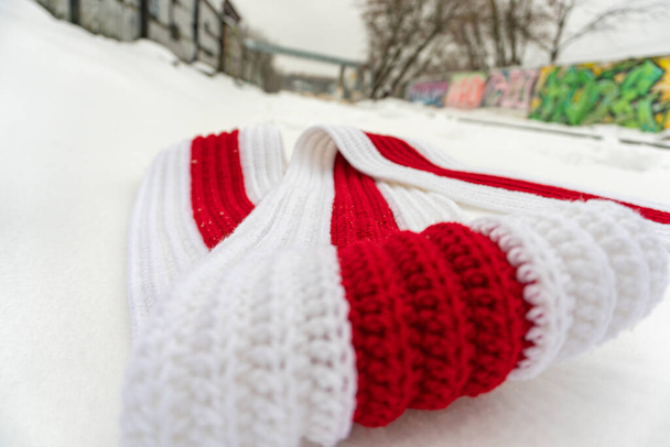 Bufanda de punto blanco-rojo-blanco en la nieve en la calle - Foto, Imagen