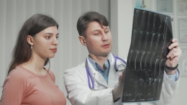 Médico masculino explicando os resultados da pesquisa de RM para sua paciente do sexo feminino - Filmagem, Vídeo