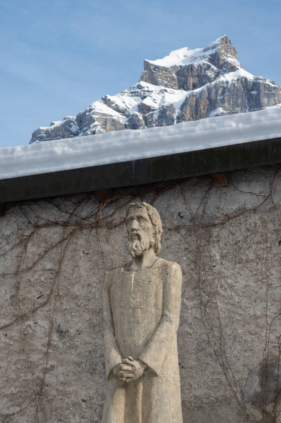 Posąg św Bruder Klaus przed murami opactwa w Engelberg i widok na górę Hahnen. - Zdjęcie, obraz