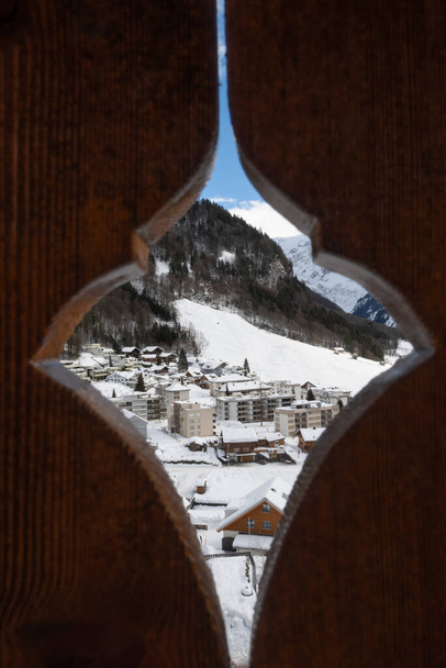 Vista invernale attraverso una recinzione di legno fino alla località sciistica svizzera nevosa di Engelberg - Foto, immagini