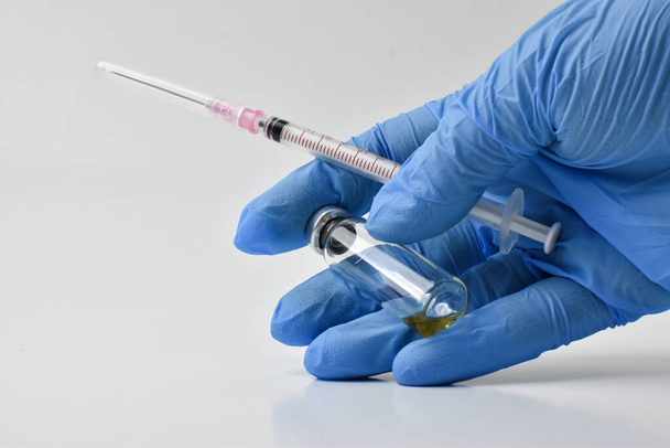 One hand holds a syringe and a glass jar of medicine - Фото, зображення