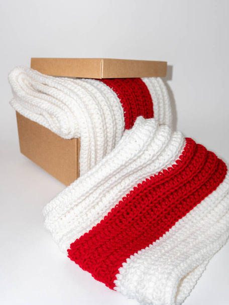 Bufanda de punto blanco-rojo-blanco en caja artesanal sobre fondo blanco - Foto, Imagen