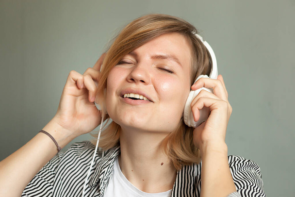 young beautiful girl in big white headphones,  listen with headphones - Zdjęcie, obraz