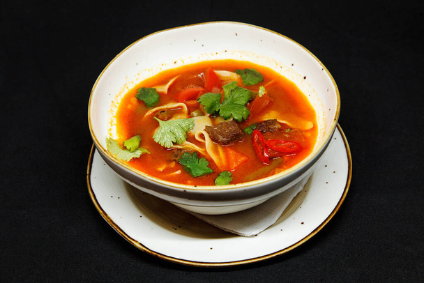 Spicy soup in a deep plate on a black background - Foto, immagini