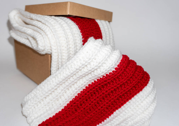 Bíle-červenobílá pletená šála v papírové krabičce na bílém pozadí - Fotografie, Obrázek