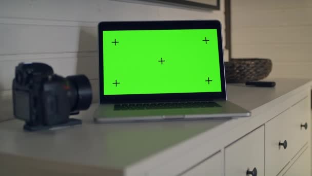 Vista di un tavolo con un computer portatile con schermo verde. La telecamera e 'qui vicino. Movimento di localizzazione. Chromakey. - Filmati, video