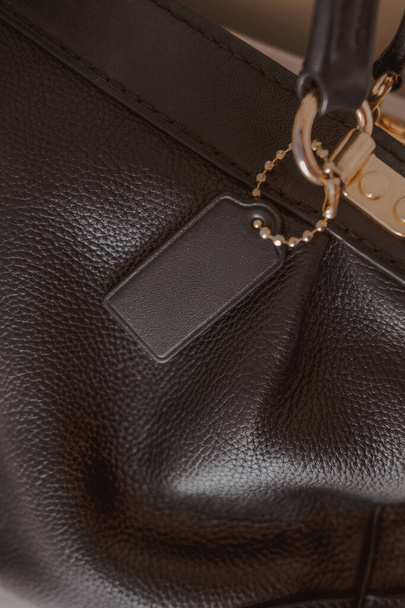 Etiqueta negra en bolsa de cuero de guijarro genuino con muebles de oro. Marca de moda maqueta, primer plano, vista superior, espacio de copia de texto - Foto, Imagen