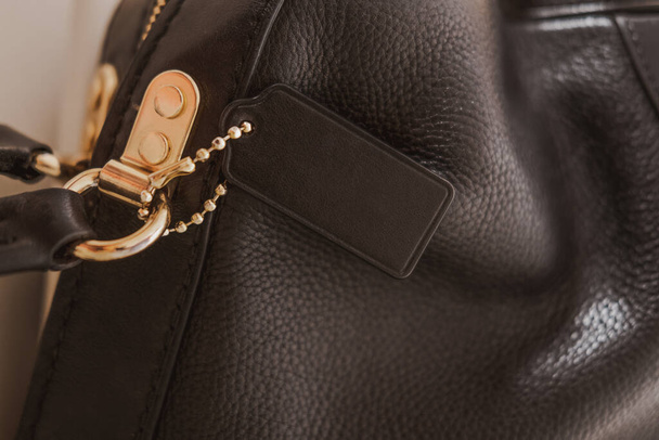 Etiqueta negra en bolsa de cuero de guijarro genuino con muebles de oro. Marca de moda maqueta, primer plano, vista superior, espacio de copia de texto - Foto, Imagen