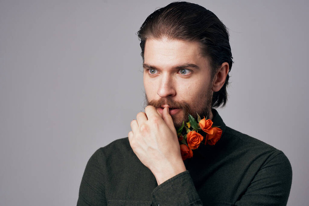 Lindo hombre elegante en una camisa negra flores en una barba decoración romance fondo gris - Foto, imagen