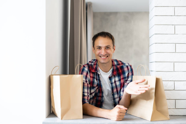 livraison, courrier et concept de personnes - homme heureux livrant de la nourriture dans un sac en papier jetable à la maison du client - Photo, image