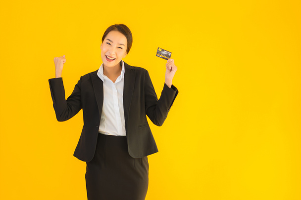 Portrait beautiful young business asian woman with credit card on yellow isolated background - Foto, Bild