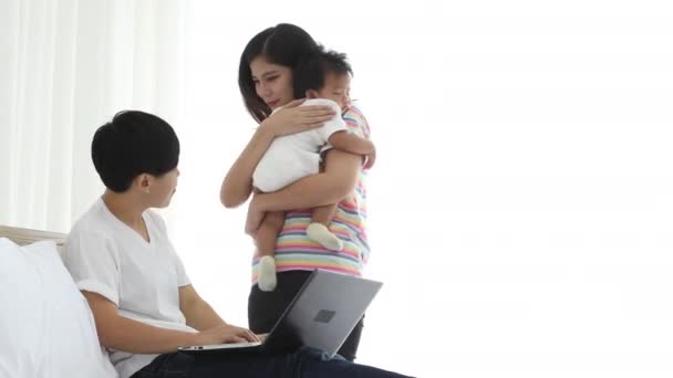Asyalı lezbiyen çift, küçük erkek bebek için online alışveriş yapıyor. Bebek gösteren dizüstü bilgisayarı olan genç bir kadın. Yaşlı kadından yatakta internetten bir şey alacak. - Video, Çekim
