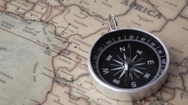 Close-up van een draaiend vintage kompas op de oude kaart. Begrippen "reizen" en "navigatiemiddel". - Video