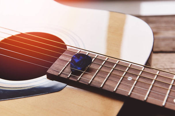 Gitarre ruht auf altem Holzgrund, Close-up Akustikgitarre und Guitar pick Musikinstrument für Freizeit oder Hobby-Leidenschaft Konzept. - Foto, Bild