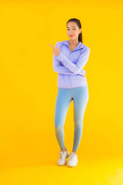 Портрет красивая молодая азиатская спортсменка со спортивной одеждой, готовая к упражнениям на желтом изолированном фоне
 - Фото, изображение