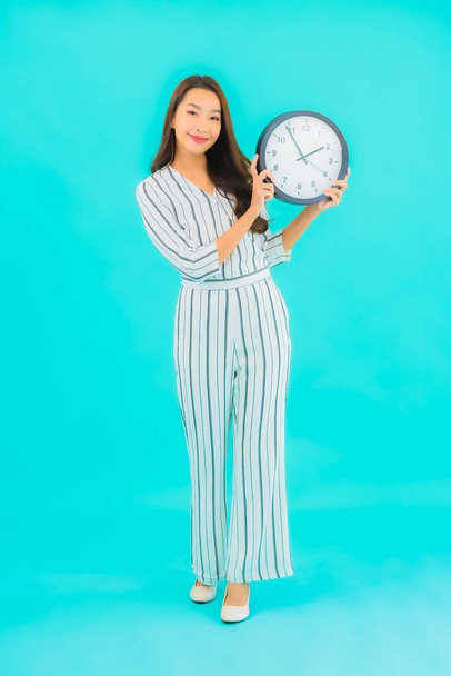 Portrait beautiful young asian woman show alarm or clock on blue background - Photo, Image