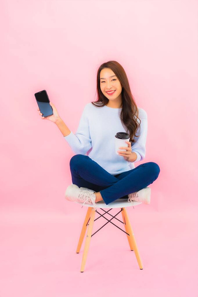 Портрет красивая молодая азиатская женщина использовать смартфон на розовый цвет изолированный фон - Фото, изображение