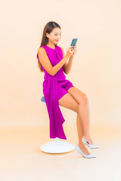 Muotokuva kaunis nuori aasialainen nainen käyttää älykästä matkapuhelinta väritaustalla - Valokuva, kuva