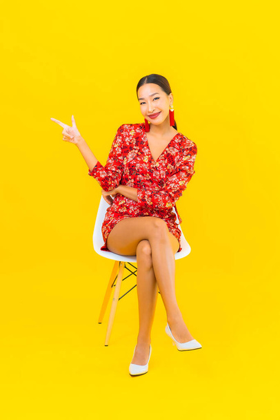 Muotokuva kaunis nuori aasialainen nainen älypuhelimella ja istua tuolilla - Valokuva, kuva