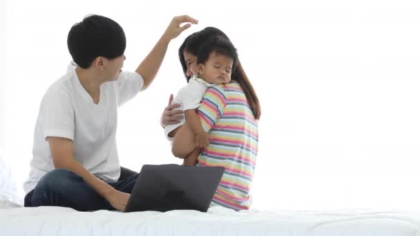 Elder woman touch head younger couple and sleeping baby while using laptop online shopping from internet on bed. Asian lesbian couple happy family concept  - Footage, Video