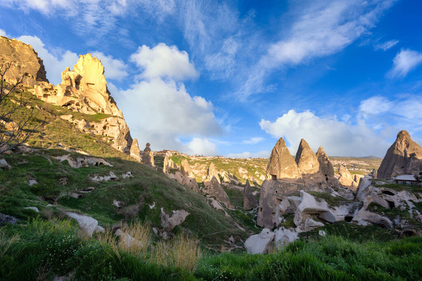 Uchisar Castle and the town are sandstone mountains filled with tunnels and windows. In the morning, the sun hits the golden peaks and blue skies of Cappadocia, Turkey. - Φωτογραφία, εικόνα