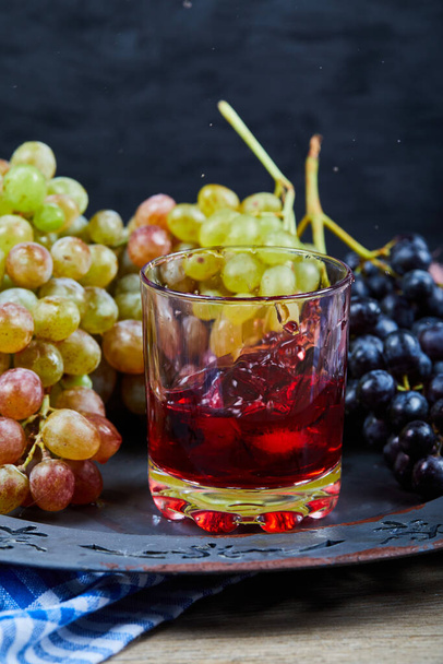 Kupa winogron i szklanka soku na ceramicznym talerzu, zbliżenie - Zdjęcie, obraz