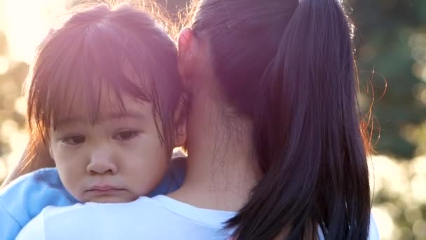 Mutter tröstet und umarmt ihre weinende kleine Tochter in einem Park. Konzept der Elternschaft. - Filmmaterial, Video
