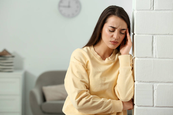 Stressed young woman near white brick wall at home. Space for text - Zdjęcie, obraz