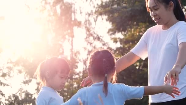 Kaksi pientä tyttöä ja äitiä treenaamassa yhdessä ulkona kesäpuistossa. Perheterveydenhuolto lomalla. - Materiaali, video