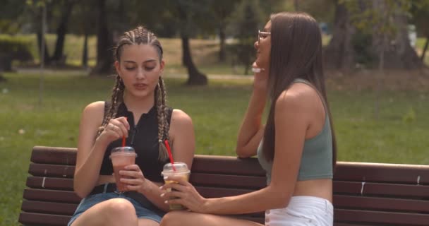 Two friends talking and looking at their phones in the park - Footage, Video