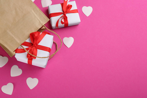 Beautiful gift boxes, paper bag and hearts on pink background, flat lay with space for text. Valentine's day celebration - Φωτογραφία, εικόνα