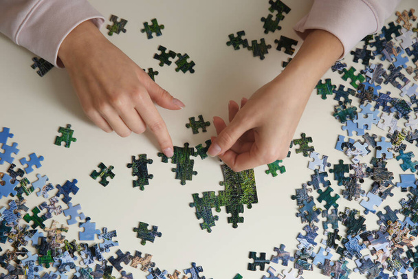 Young woman playing with puzzles at table, top view - Foto, afbeelding