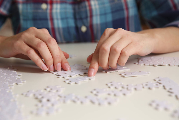 Young woman playing with puzzles at table, closeup - Foto, Imagem