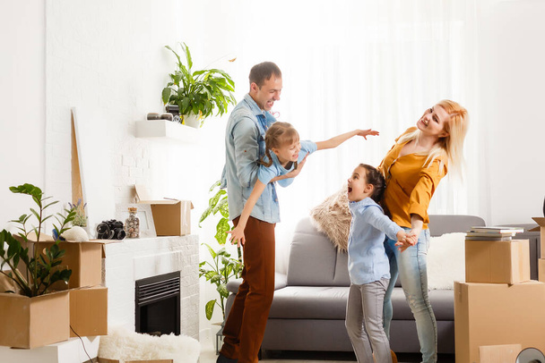 Happy family with cardboard boxes in new house at moving day. - Φωτογραφία, εικόνα