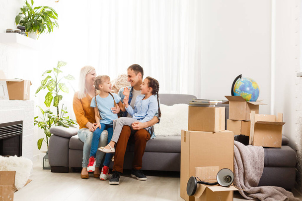 Happy family with cardboard boxes in new house at moving day. - Foto, Imagem