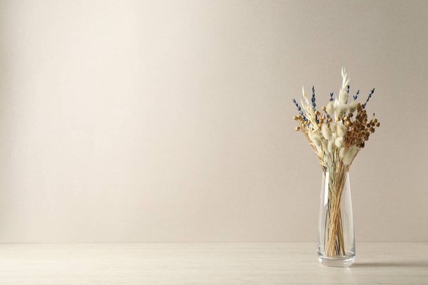 Dried flowers in vase on table against light background. Space for text - Foto, Imagen