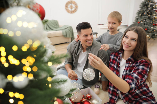 Happy family with cute child decorating Christmas tree together at home - Foto, Imagem