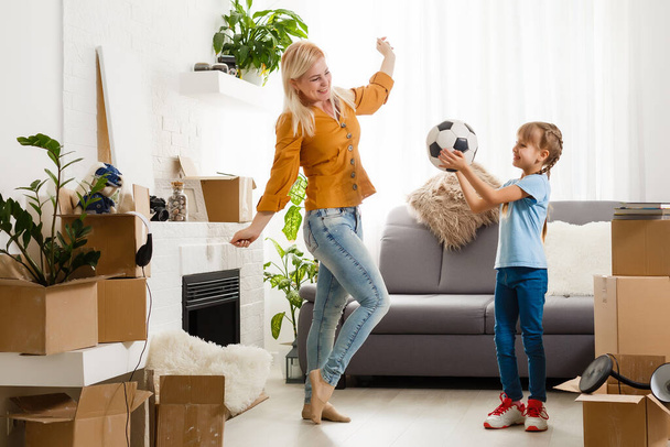Muito jovem mãe e sua filhinha fofa se divertindo em novo apartamento e desempacotando caixas móveis - Foto, Imagem