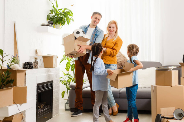 Famille heureuse avec des boîtes en carton dans une maison neuve au jour du déménagement. - Photo, image