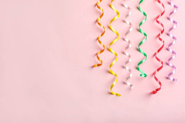 Colorful serpentine streamers on pink background, flat lay. Space for text - 写真・画像