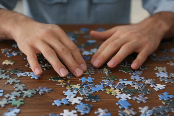 Man playing with puzzles at wooden table, closeup - Foto, Bild