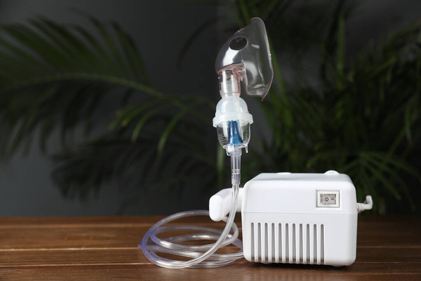 Modern nebulizer with face mask on wooden table indoors, space for text. Inhalation equipment - Fotó, kép