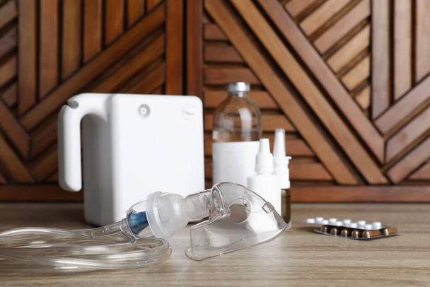 Modern nebulizer with face mask and medications on wooden table. Inhalation equipment - Foto, Imagem