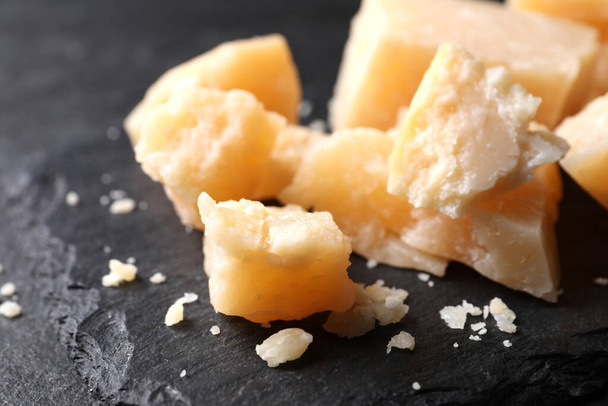 Pieces of delicious parmesan cheese on slate plate, closeup - Foto, afbeelding