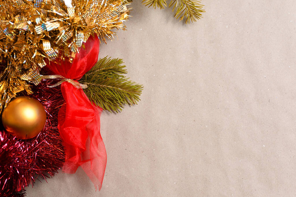 Antecedentes sobre papel artesanal son cuentas de color naranja, oropel de oro y rojo, ramas de abeto verde. Decoración, decoración para el Año Nuevo y Navidad - Foto, Imagen