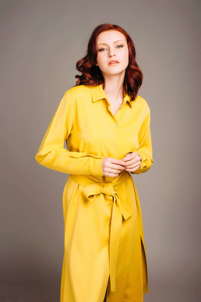 Mujer jengibre joven en vestido de camisa amarilla. Aspecto femenino brillante, estilo casual limón. Retrato de moda sobre fondo de estudio neutro. - Foto, imagen