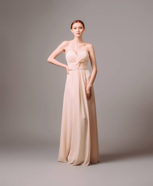 Bridesmaid's dresses. Elegant moscato dress. Beautiful pink chiffon evening gown. Studio portrait of young happy ginger woman. Transformer dress idea for an event.  - Valokuva, kuva