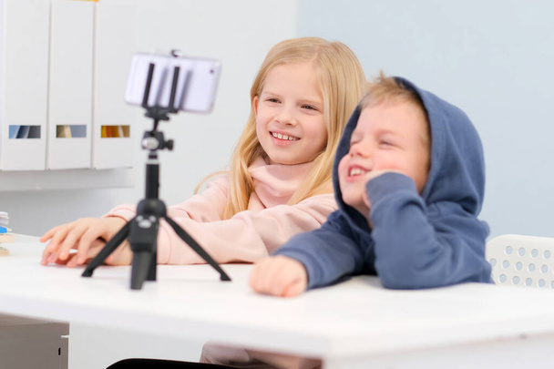 Kids bloggers talking with followers, live streaming, looking to smartphone screen at home. Boy and Girl making selfie or call friends and parents. Social media, instagram, stay home and quarantine - Fotoğraf, Görsel