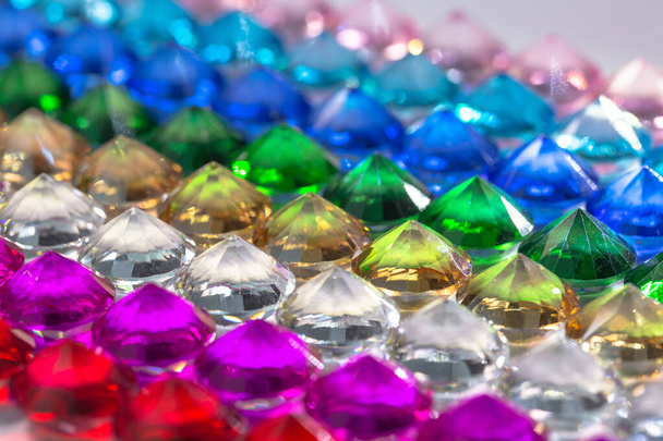 Kleurrijke diamanten worden netjes op rij op een witte vloer gerangschikt. - Foto, afbeelding