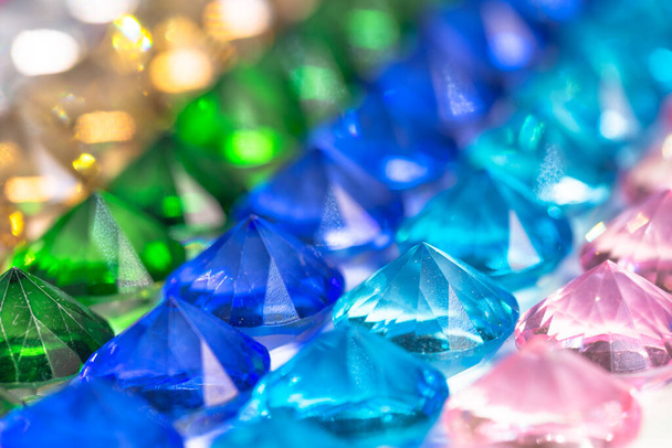 Diamantes coloridos são organizados ordenadamente em uma fileira em um piso branco. - Foto, Imagem